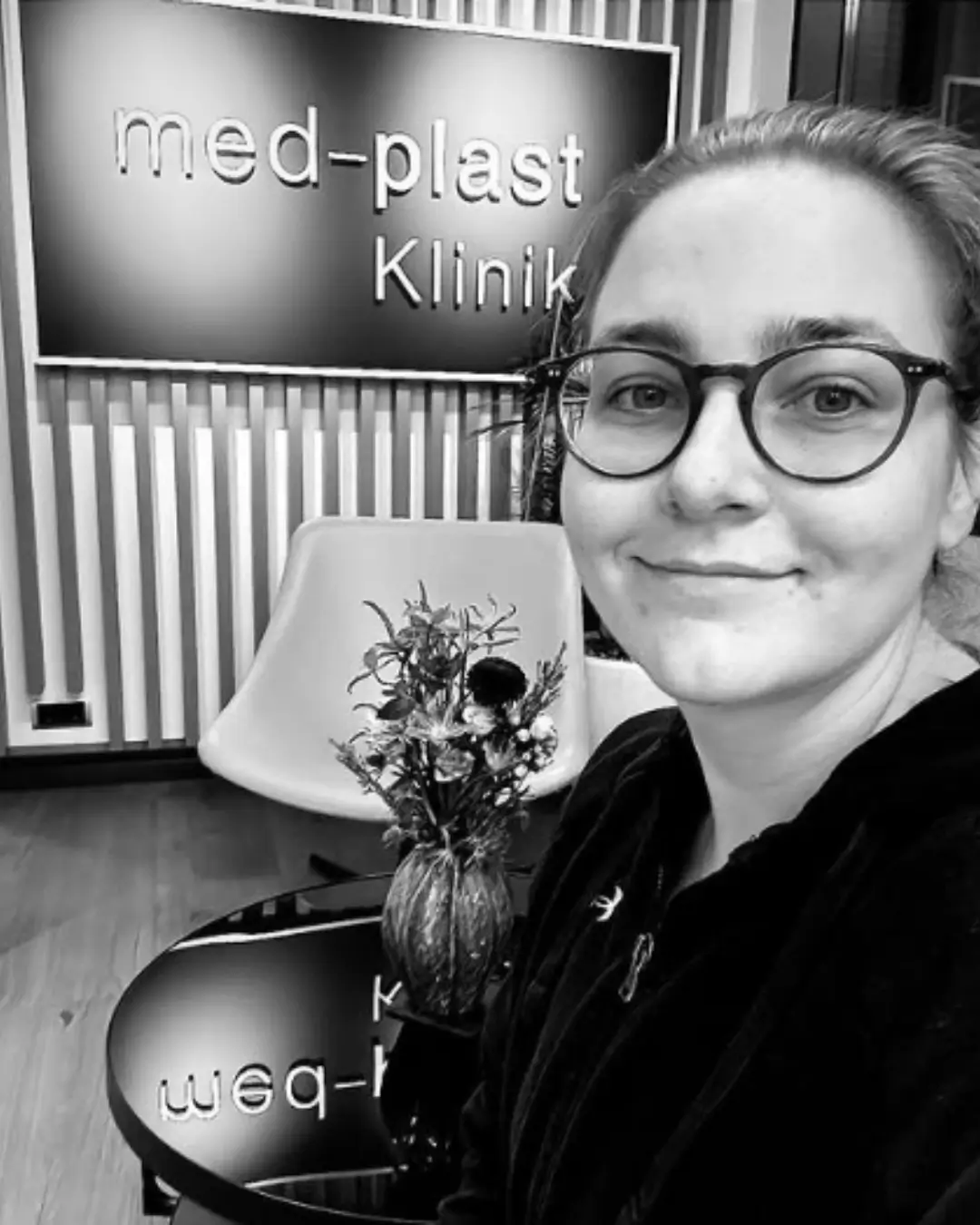 Lipödem-Patientin beim Besuch in der med-plast Klinik, lächelnd im Wartebereich vor dem Klinikschild